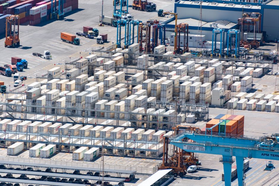 Bird's eye view of a logistics warehouse with shipping containers and trucks.